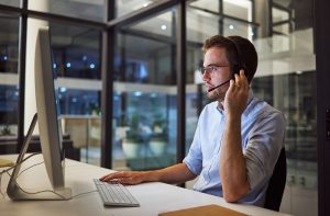 An IT professional speaks with a client via a headset