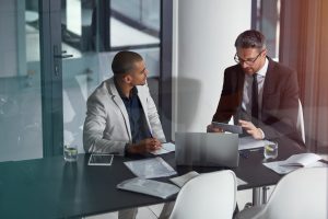 Two men discuss IT over a laptop in a conference room